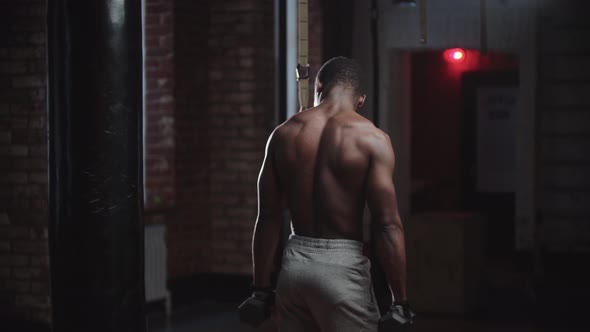 A Black Handsome Man Pumping His Hands Muscles with Dumbbells in the Gym  View of His Back