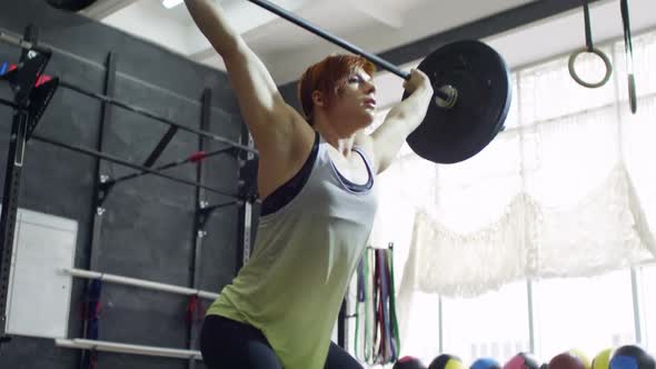 Sportswoman Lifting Barbell Overhead