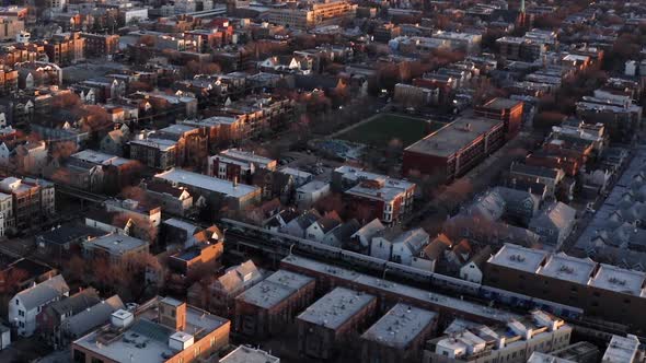 Subway Train Traveling in Urban Neighborhood. Zoom Out Reveals Chicago Skyline at Sunrise. Aerial Vi