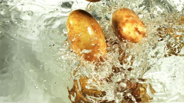 Potatoes Fall Under Water with Splashes and Air Bubbles