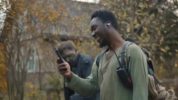 Afro Man Listening To Music in Headphones and Using Cellphone Ignoring Zombie 