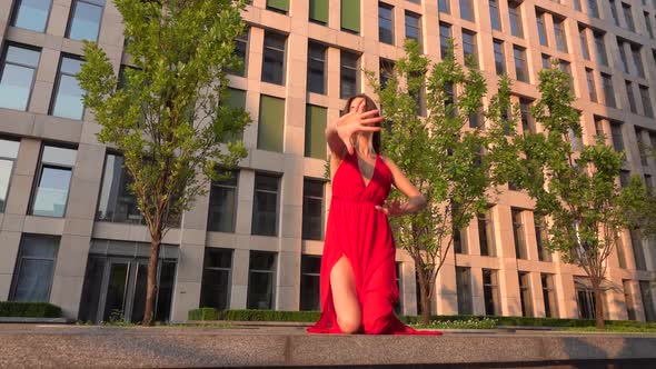 Beautiful Young Girl Dancing on the Street of a Modern Building of a Business Center in the Sunset