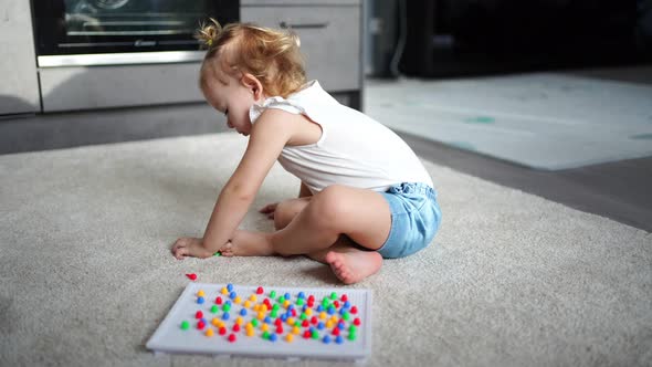 Pretty Little Girl Playing with Mushroom Nail Mosaic at Home