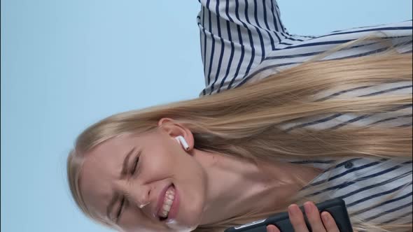 Young Blonde Woman Getting High While Listening To the Music and Singing on Blue Background