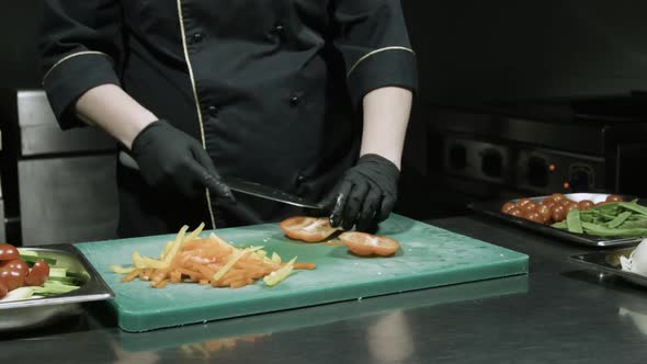 Cook's Hands in Black Gloves Chopping Peppers