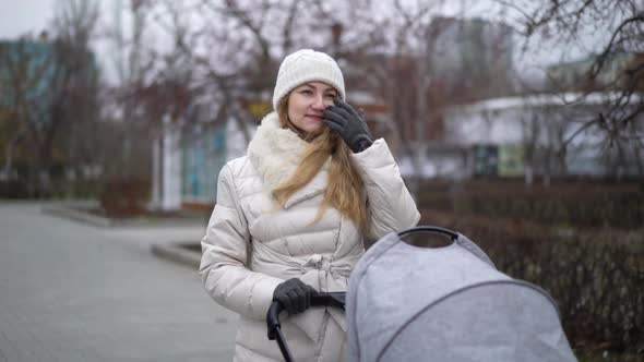 Young Mother Walking with a Child in Pram. Autumn Season