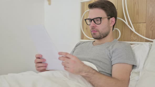 Beard Young Man Reading Documents in Bed