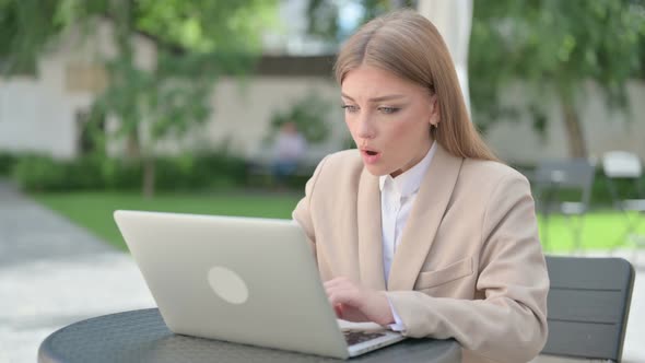 Young Businesswoman Feeling Shock While Using Laptop in Outdoor Cafe
