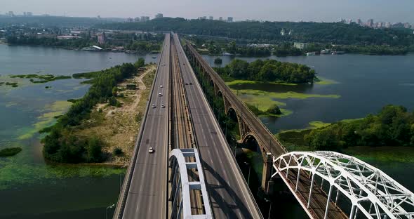 Aerial top view of automobile and railroad Darnitsky bridge across Dnieper river from above