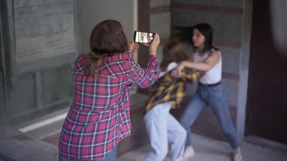 Back View Teenage Girl Filming Fight of Two Angry Classmates on Smartphone