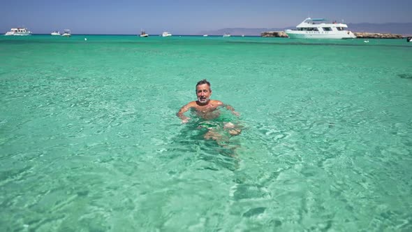 Wide Shot Happy Relaxed Caucasian Man Swimming in Turquoise Mediterranean Sea Waters Smiling Talking