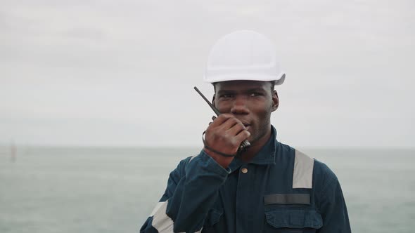 African American Seaman Speaks with VHF Walkietalkie Radio in Hands