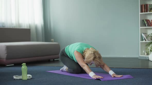Athletic Mature Woman Practicing Yoga Poses at Home, Fitness and Health