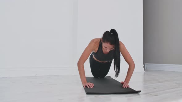 Young Sexy Brunette Woman in Sportswear Performs Pushups Kneeling at Home on a Rug