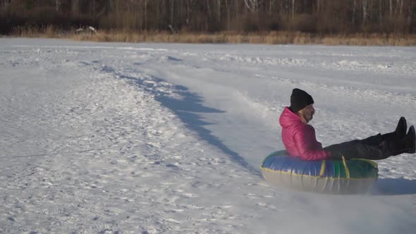 Woman Rides a Tube From a Slide in Winter in a Snowfall