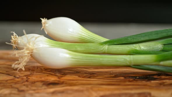 Super Slow Motion Shot of Fresh Spring Onion Falling on Wooden Cutting Board at 1000Fps.