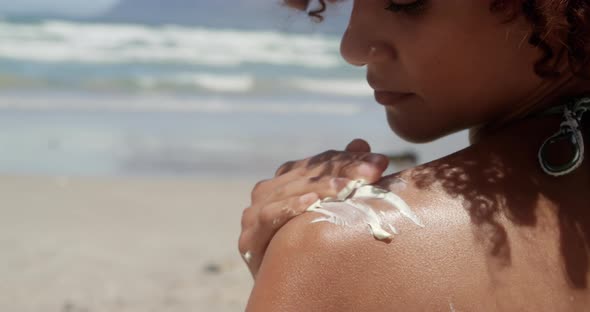 Woman applying sunscreen on shoulders at beach in the sunshine 4k