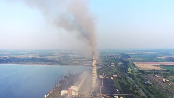 Aerial view of coal power plant high pipes with black smokestack polluting atmosphere.