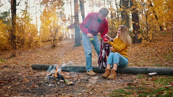 Female Frying Marshmallow on Campfire Sitting on Log in Autumn Forest