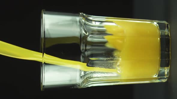 Vertical Video Juice Pouring Into Faceted Glass Isolated on Black Background