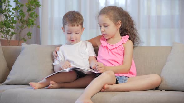 Cute Children,sister with a Younger Brother, Looking at a Book Magazine Textbook Dictionary Tablet
