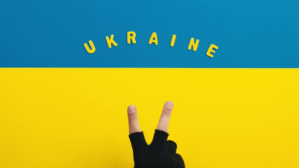 Hand with Victory Symbol on Ukrainian Flag Background