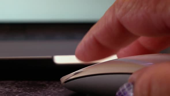 Close up first person view of fingers scrolling and clicking on a white computer mouse