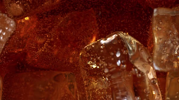 Super Slow Motion Detail Shot of Fizzing Cola Lemonade and Floating Ice Cubes at 1000 Fps alt
