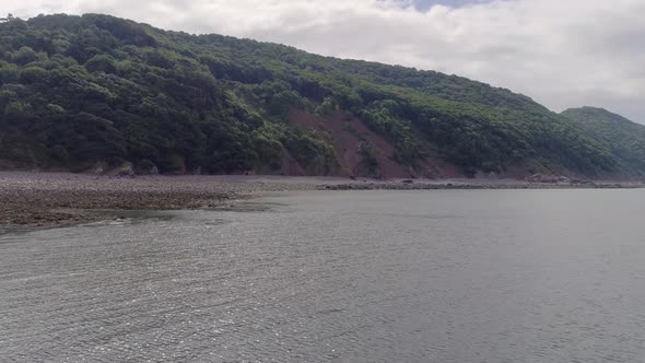 Wide aerial tracking forward over the sea in towards the cliffs to the West of Porlock Weir, Somerse