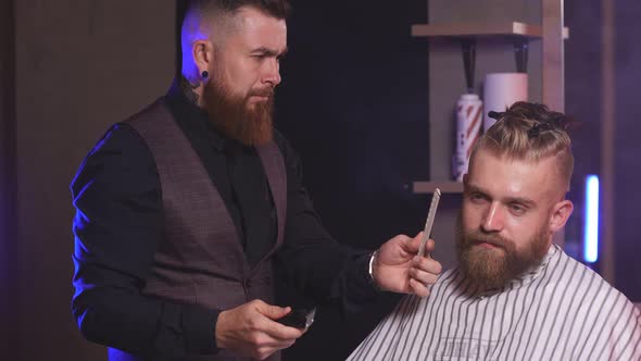 Professional Hairdresser Shaving a Beard To Rich Clients in Barbershop