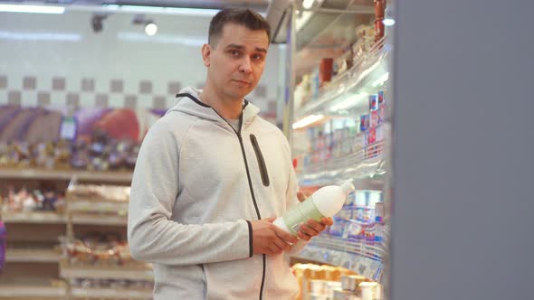 a Suspicious Middleaged Man Opens a Bottle of Food Store