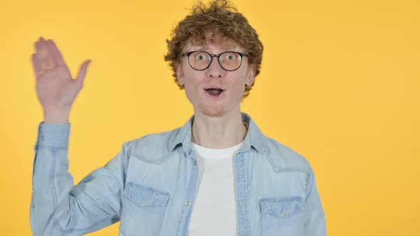 Welcoming Redhead Young Man Waving Yellow Background