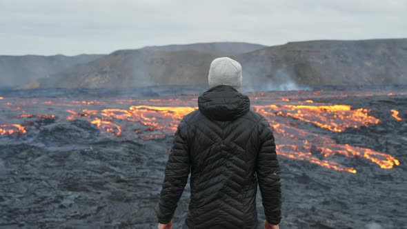 Man Looking Out Over Flowing Lava In Burning Landscape