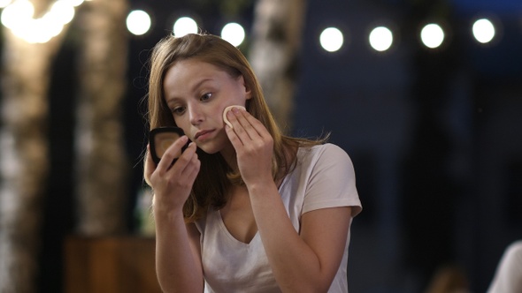 Beautiful woman checking her makeup outdoors in the evening