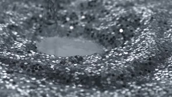 Water drop making ripple on water filled with glitter, Slow Motion