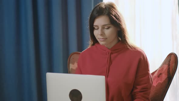 Pretty smiling brunette business woman working in home office typing letter closing a computer