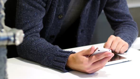 Mid-section of man using digital tablet and mobile phone