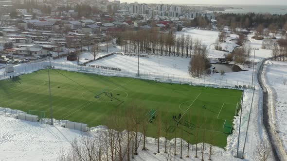 Football Players On The Field In Snowy Landscape At Winter In Reykjavik, Iceland. wide aerial
