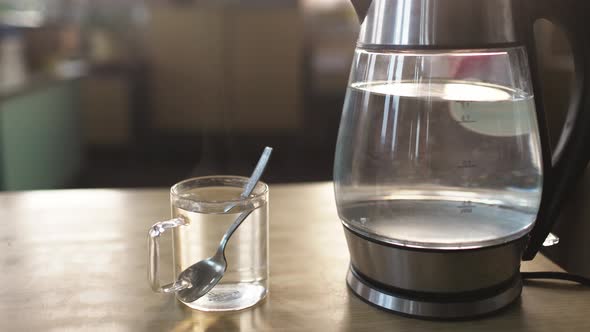 Slider Shot of a Transparent Kettle with Water Boils