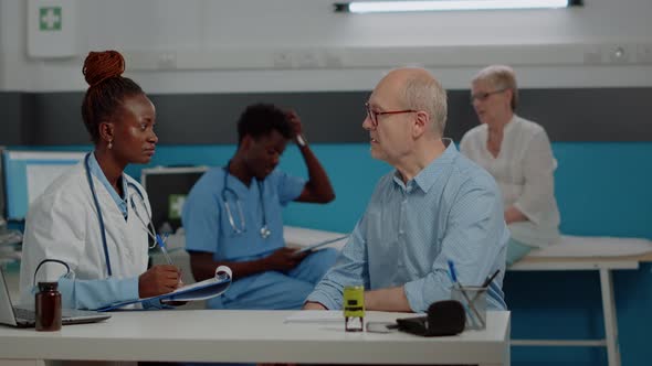 Healthcare Specialist Discussing with Old Patient at Desk