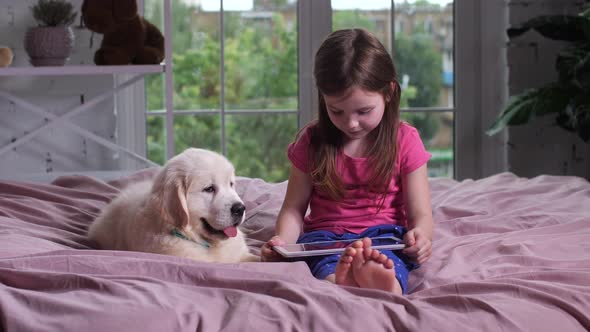 Child Watching Video with Puppy on Bed