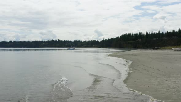 Drone View Flying Along Beach Waterfront Sailboat Floating In Port Townsend Bay