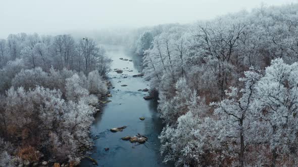 Scenic winter landscape. Аerial view of snow covered forest around beautiful river