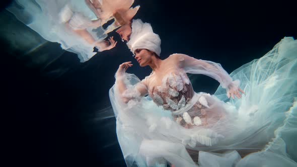 Stunning Underwater Fairy is Swimming Under Surface of Magical Sea or Lake Touching Water By Hand