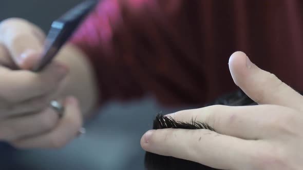 Close-up Barber Cuts Off a Man's Black Hair with Scissors