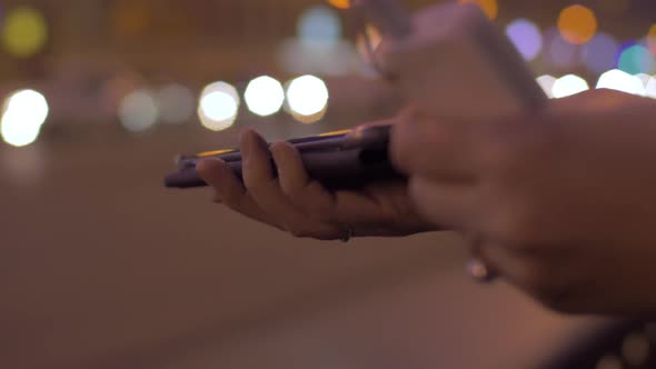 Young Girl in Evening Street Connects To the Mobile Phone Portable Charger