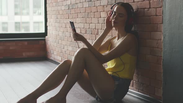 Young Woman Enjoying Music Near Wall