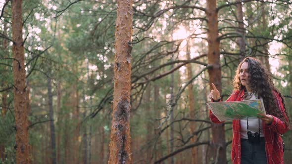 Young Woman Tourist with Backpack and Binoculars Is Walking Through Wood Then Standing and Looking