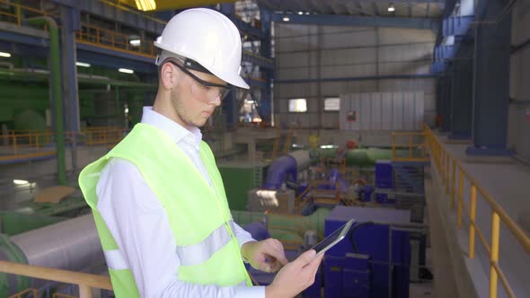 Engineer works with his tablet at the factory.