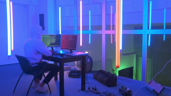 Hacker Working Place: Hacker Working in a Room with Colored Neon Lights